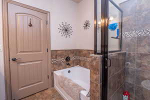 Primary bath features both a soaking tub with tile surround and mosaic accent band, plus a separate glass-door walk-in shower. Oil-rubbed bronze fixtures throughout tie it all together.