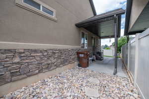 Stone-clad exterior base and river rock landscaping along the side of the home leading to the covered patio. Low-maintenance design with clean curb appeal all the way around.
