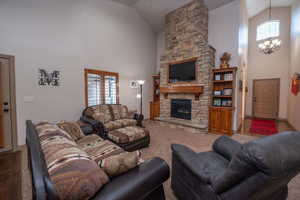 Show-stopping great room with vaulted ceilings, floor-to-ceiling stacked stone fireplace, built-in wood cabinetry, and a chandelier in the entry beyond. This room owns the whole house.