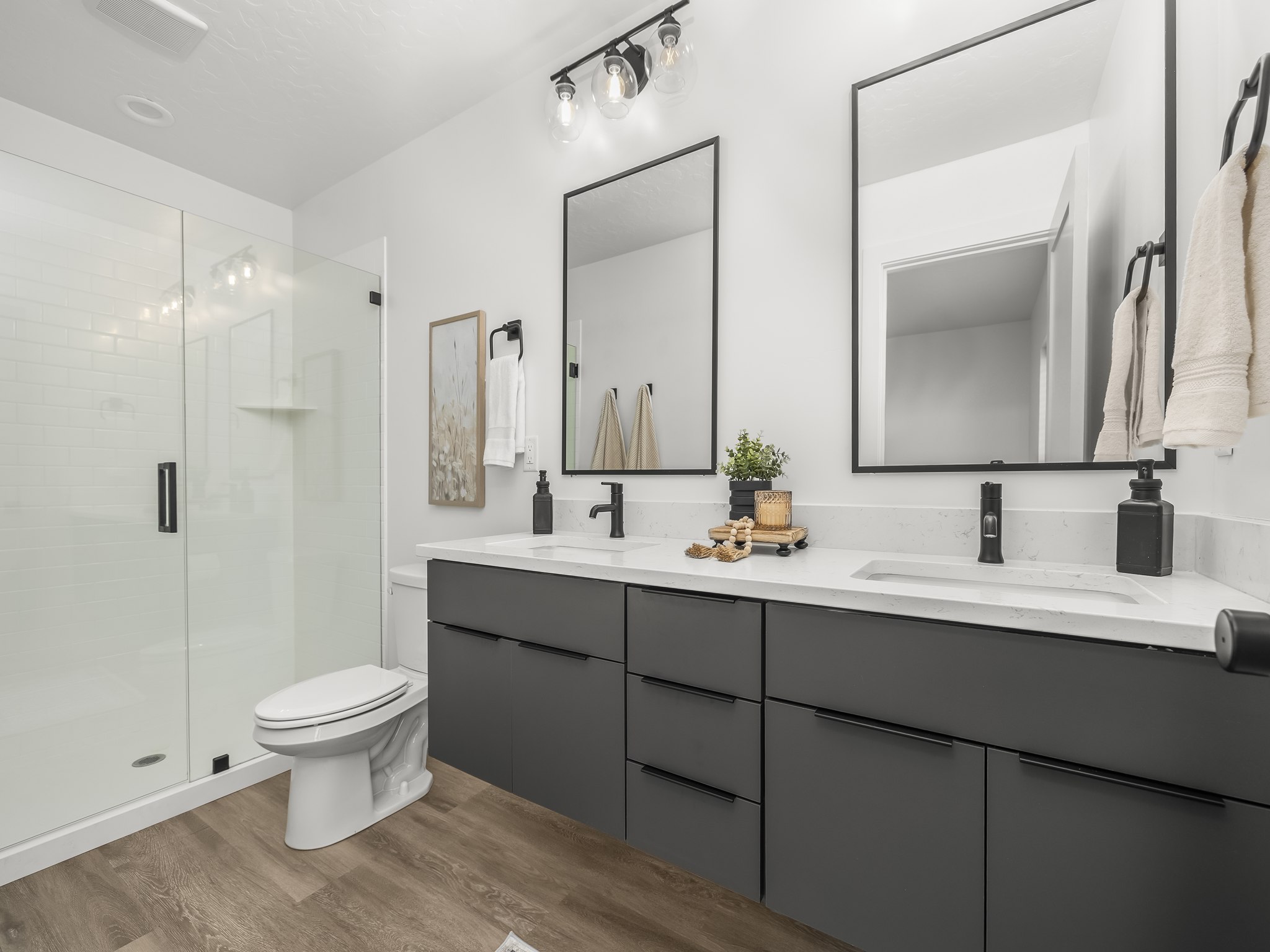 Contemporary bathroom featuring a double vanity with dark cabinetry and white countertops
