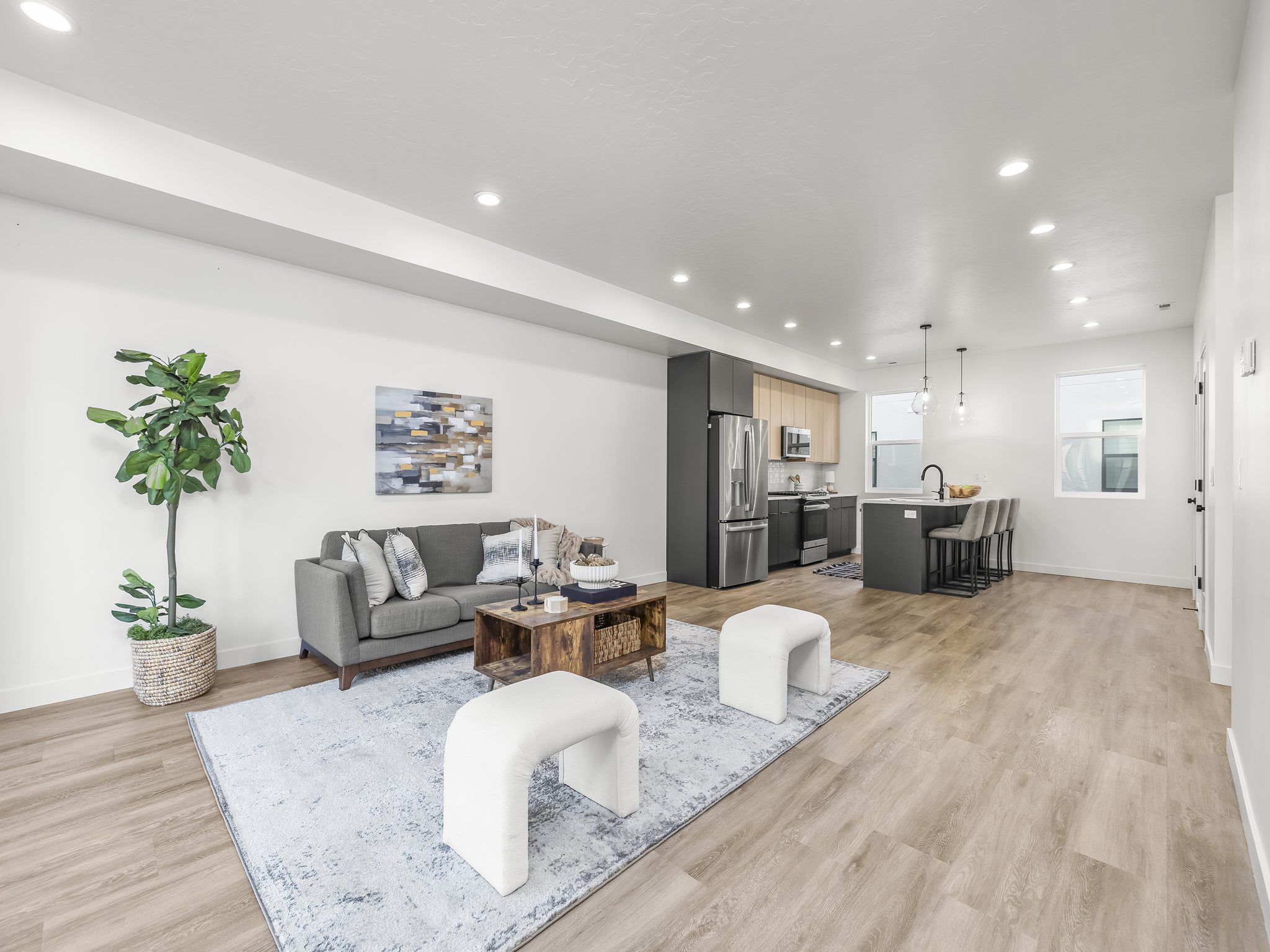 Open-concept living space featuring wood-finish flooring, recessed lighting, and a kitchen with stainless steel appliances