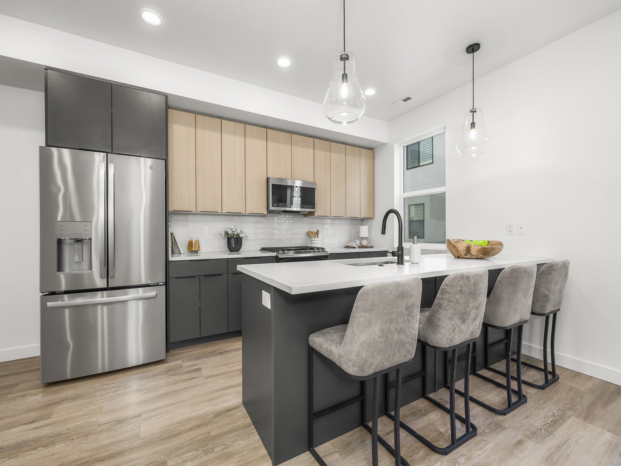 Modern kitchen featuring stainless steel appliances, a white subway tile backsplash, and a large island with seating