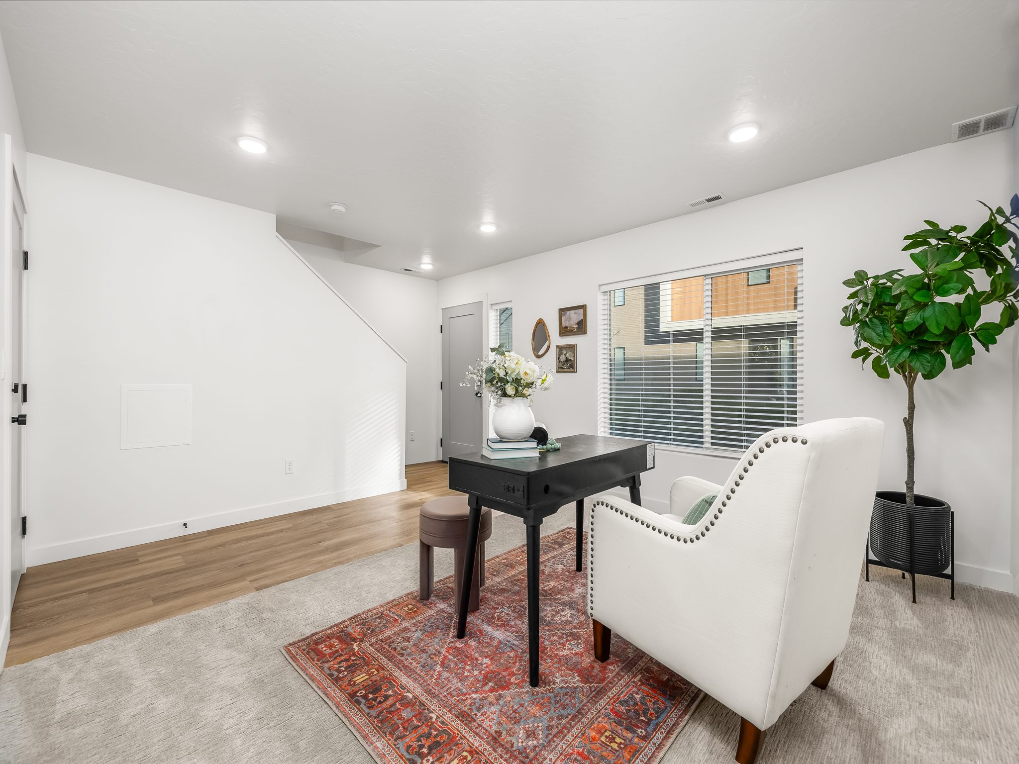Bright interior space featuring a window with blinds, recessed lighting, wood-finish flooring, and light-toned carpeting