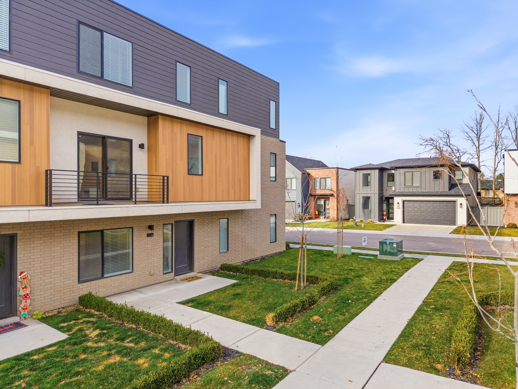 Contemporary multi-story exterior featuring a mix of brick, horizontal siding, and wood-finish paneling