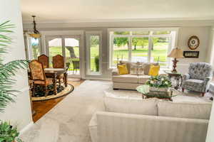 Spacious living room featuring a large bay window, light grey wall paint, and crown molding