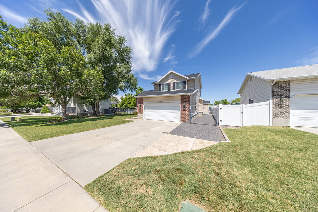 Two-story residence featuring a two-car garage, brick accents, and a fenced side yard