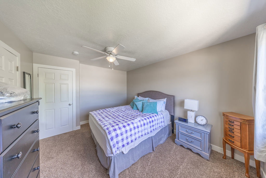 Bedroom featuring neutral wall paint, textured carpeting, and a ceiling fan with integrated lighting