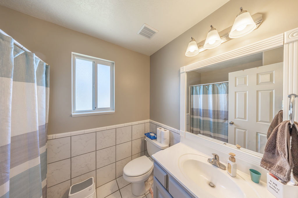 Full bathroom featuring a single vanity, a framed mirror, and a window