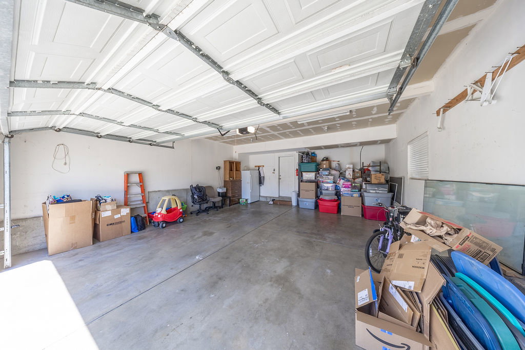 Spacious garage with concrete flooring, white overhead garage door, interior access door, and a built-in window