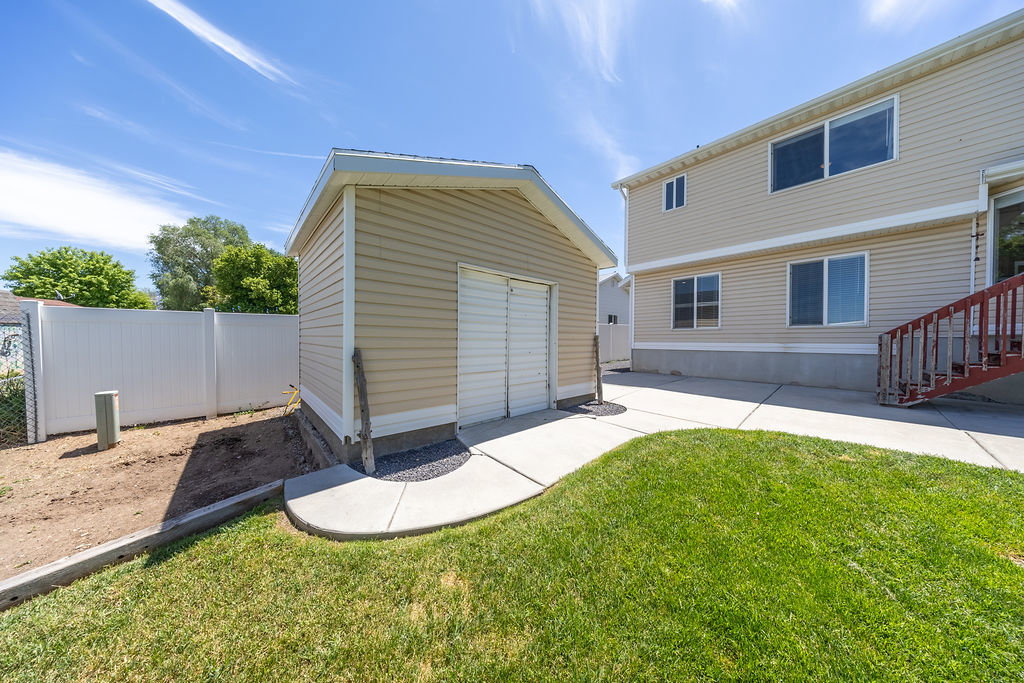 Detached utility shed featuring horizontal siding and a roll-up door
