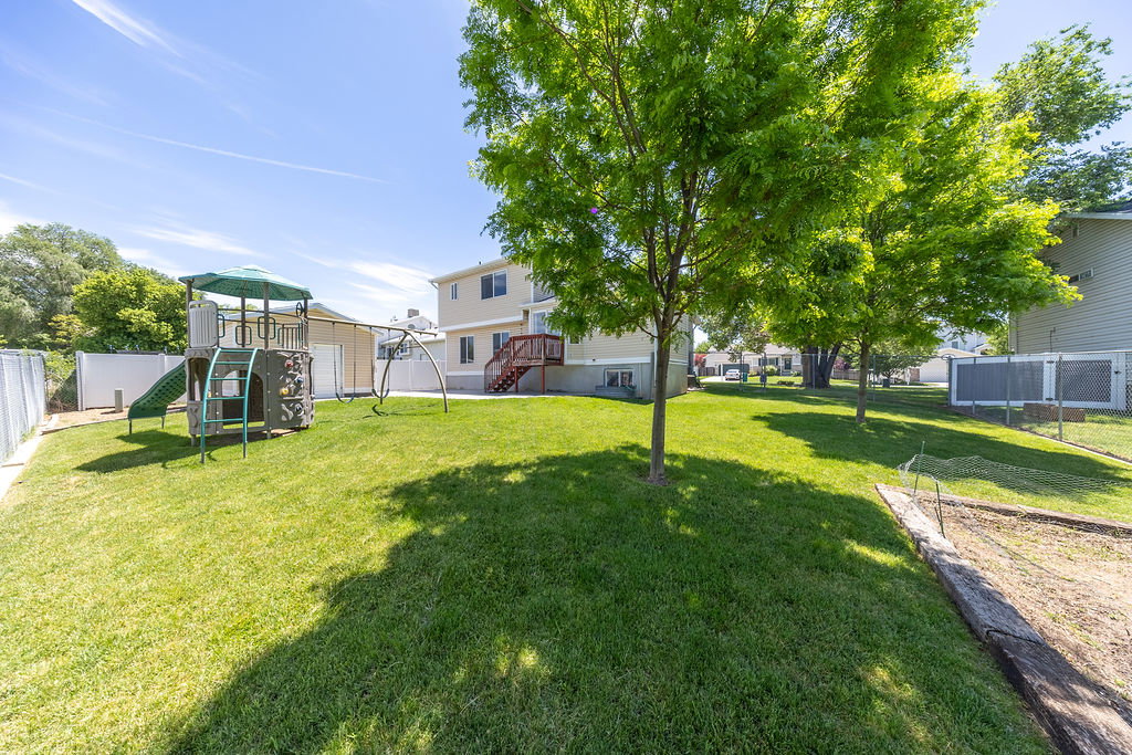 Spacious backyard featuring a manicured lawn, established shade trees, and a privacy fence
