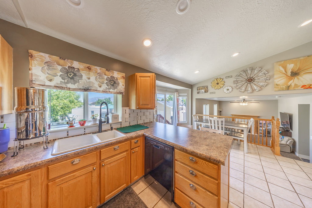 Kitchen featuring wood cabinetry, a double basin sink with a gooseneck faucet, and laminate countertops