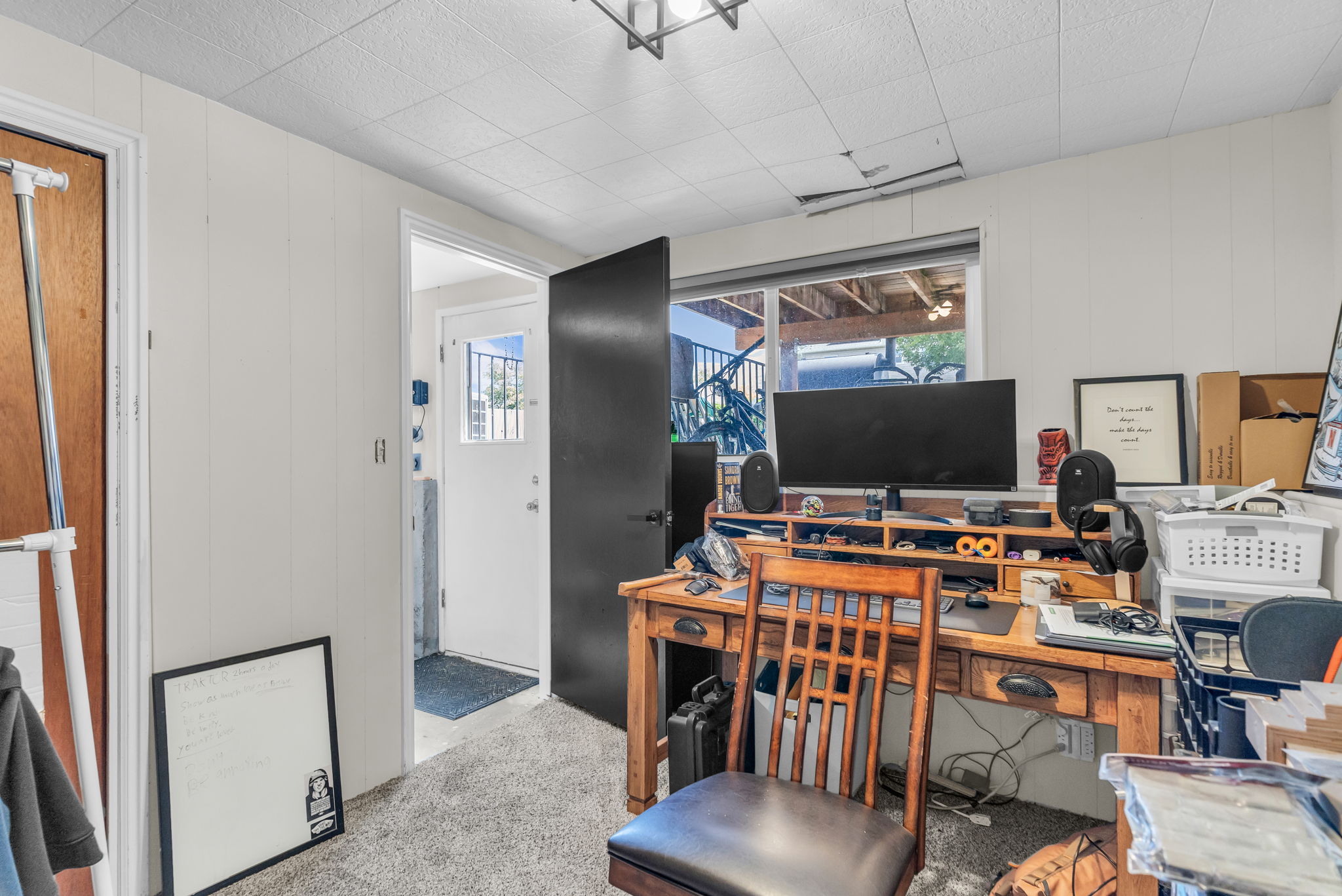 Carpeted room featuring vertical panel walls, a wood-finish desk with drawers, and a large window