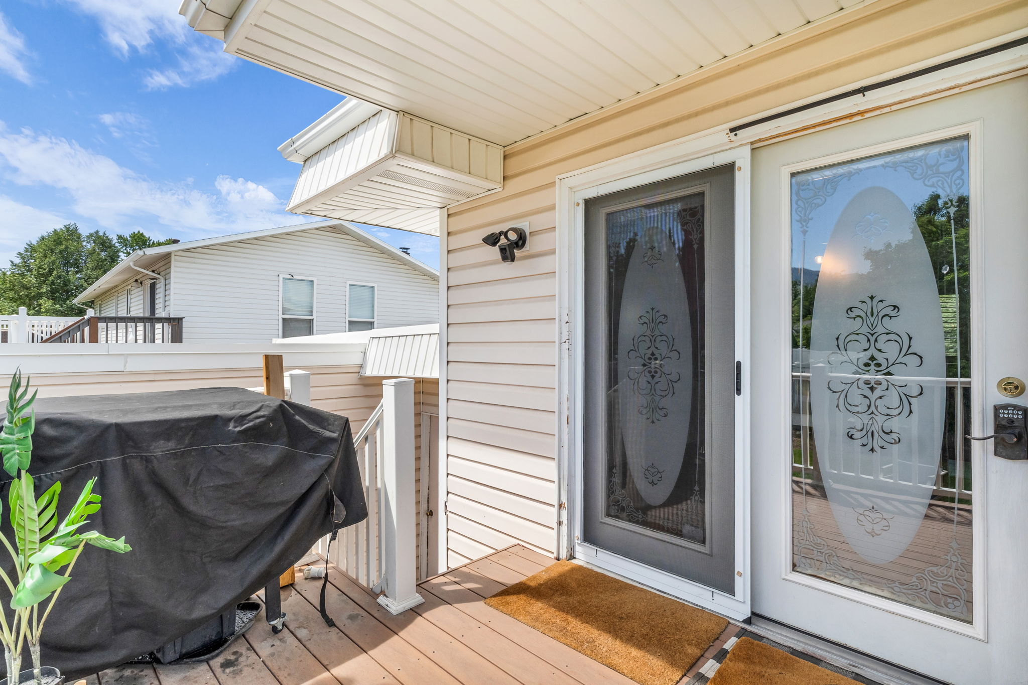 Exterior entrance featuring a decorative glass door, storm door, and digital keypad entry