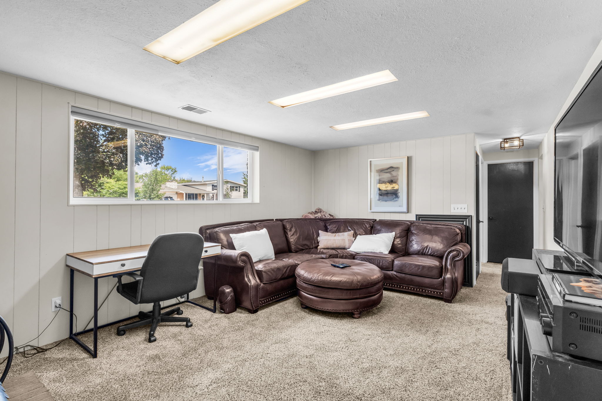 Spacious room featuring carpeting, paneled walls, and a large window