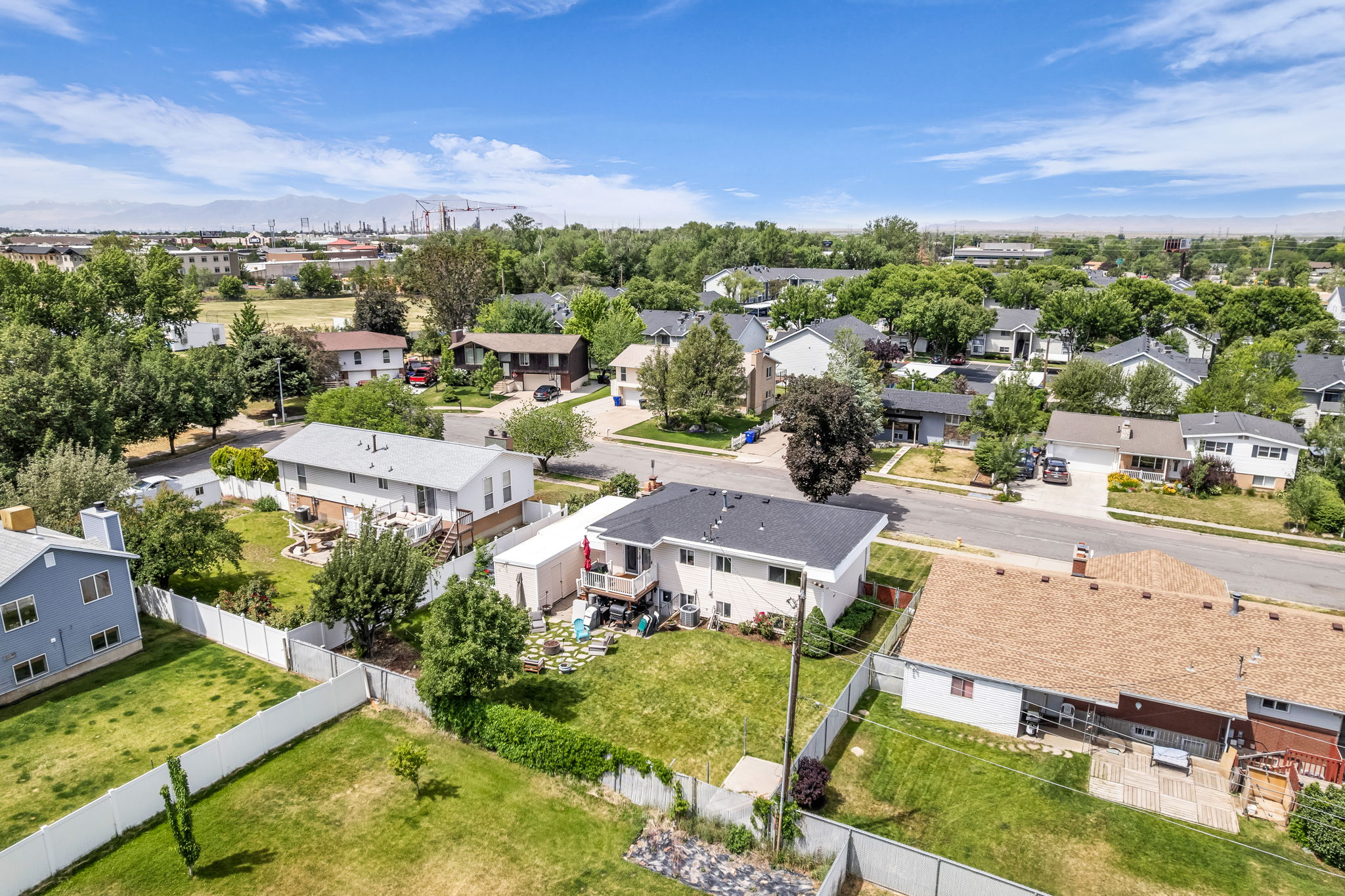 Expansive residential property featuring a large backyard with a white privacy fence and mature trees