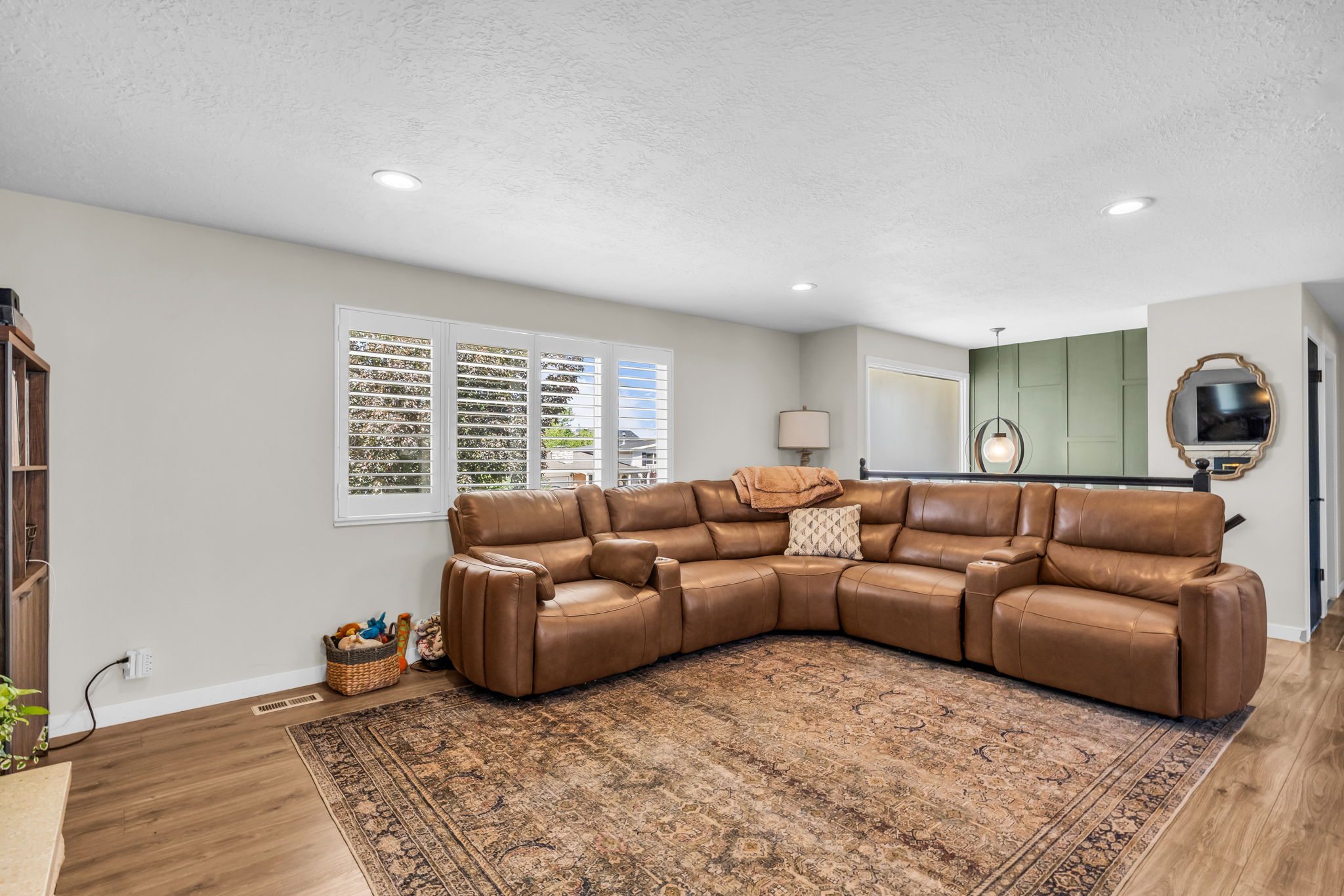 Spacious living area featuring wood-finish flooring, recessed lighting, and white plantation shutters