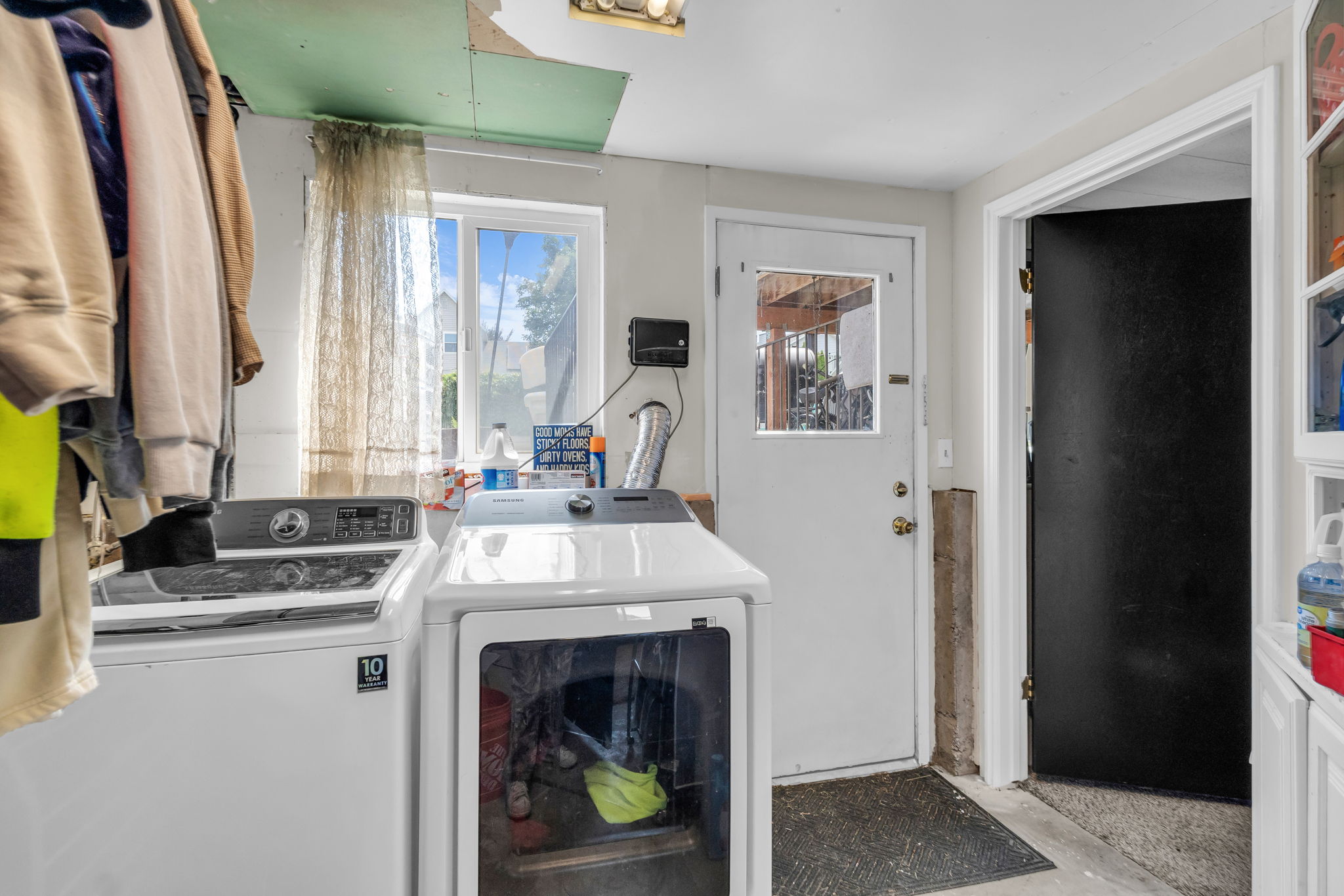 Utility area featuring a window, white door with a window pane, and a built-in white storage cabinet with glass-front uppers