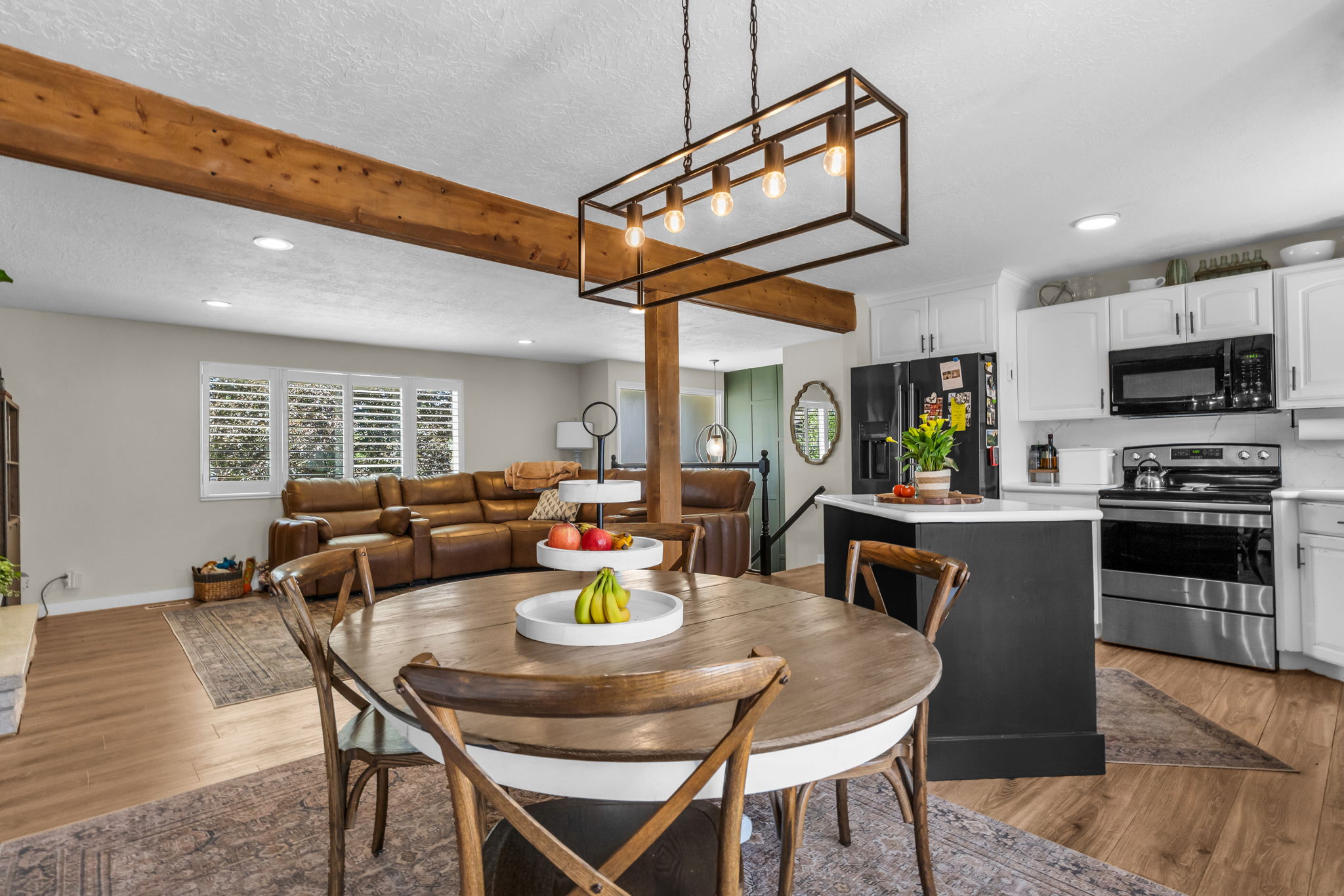 Spacious dining area featuring a round wood table and a contemporary black linear chandelier