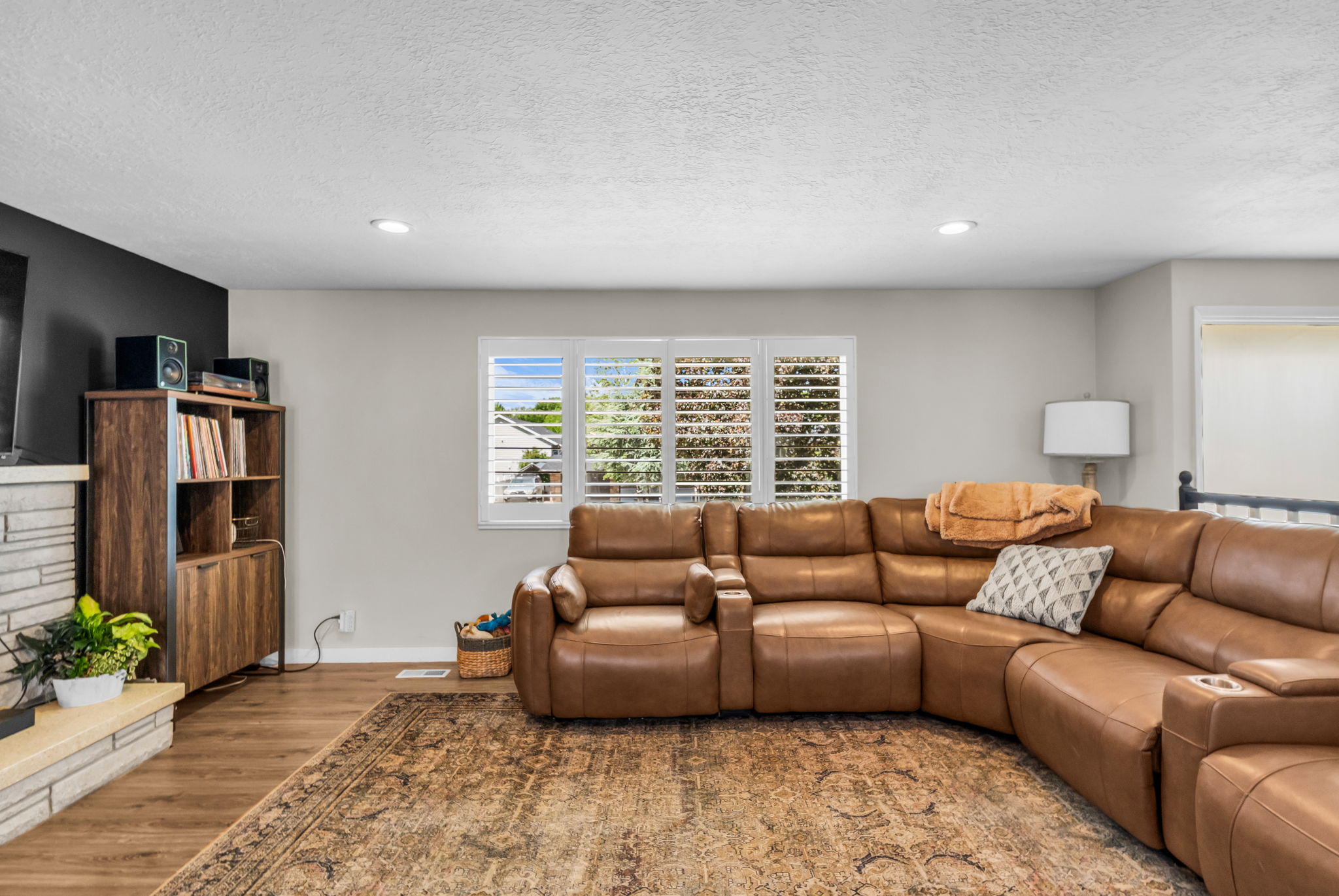 Living area featuring wood-finish flooring, a stone fireplace surround, and recessed ceiling lighting