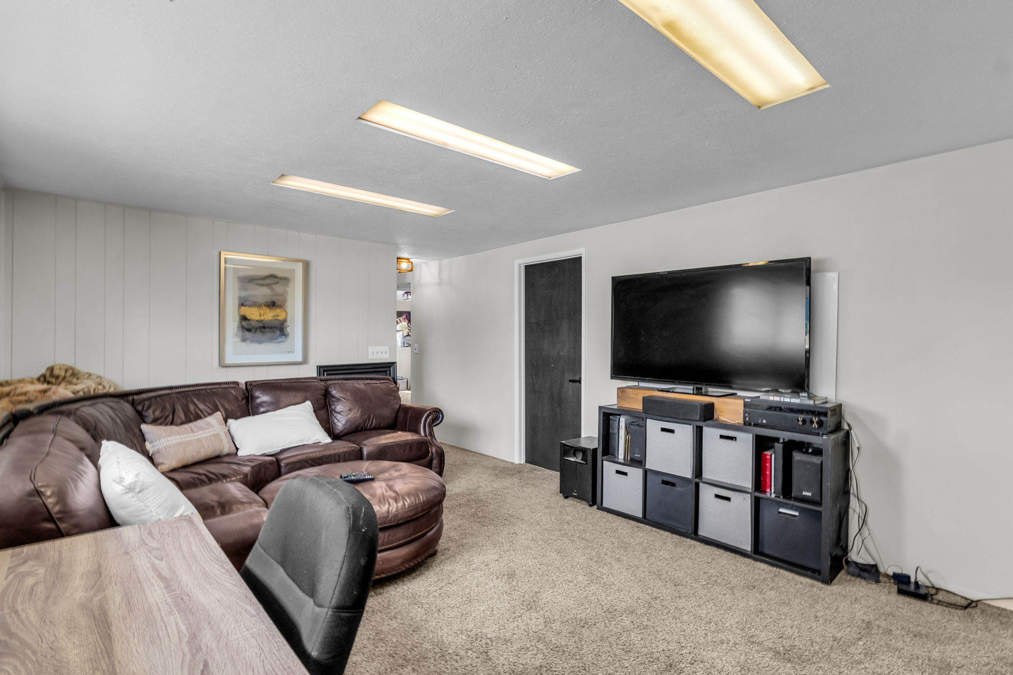 Carpeted room featuring a built-in fireplace, a dark wood-finish door, and recessed fluorescent lighting