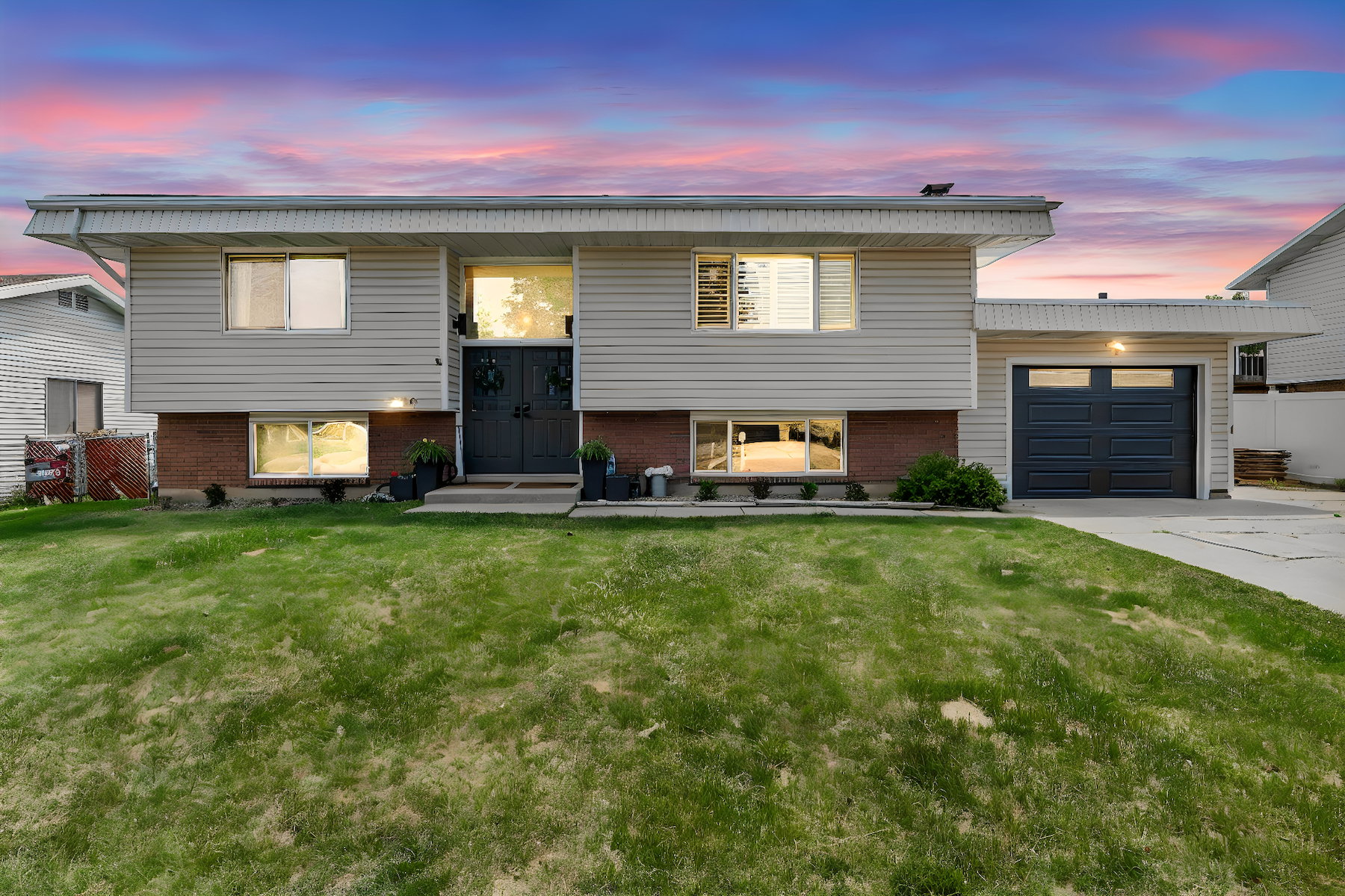 Split-level residence featuring light siding, brick accents, and a dark double entry door