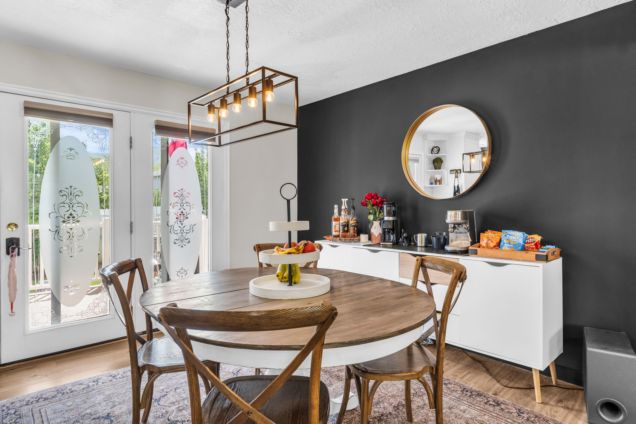 Dining area featuring a contemporary linear chandelier, a dark accent wall, and wood-finish flooring