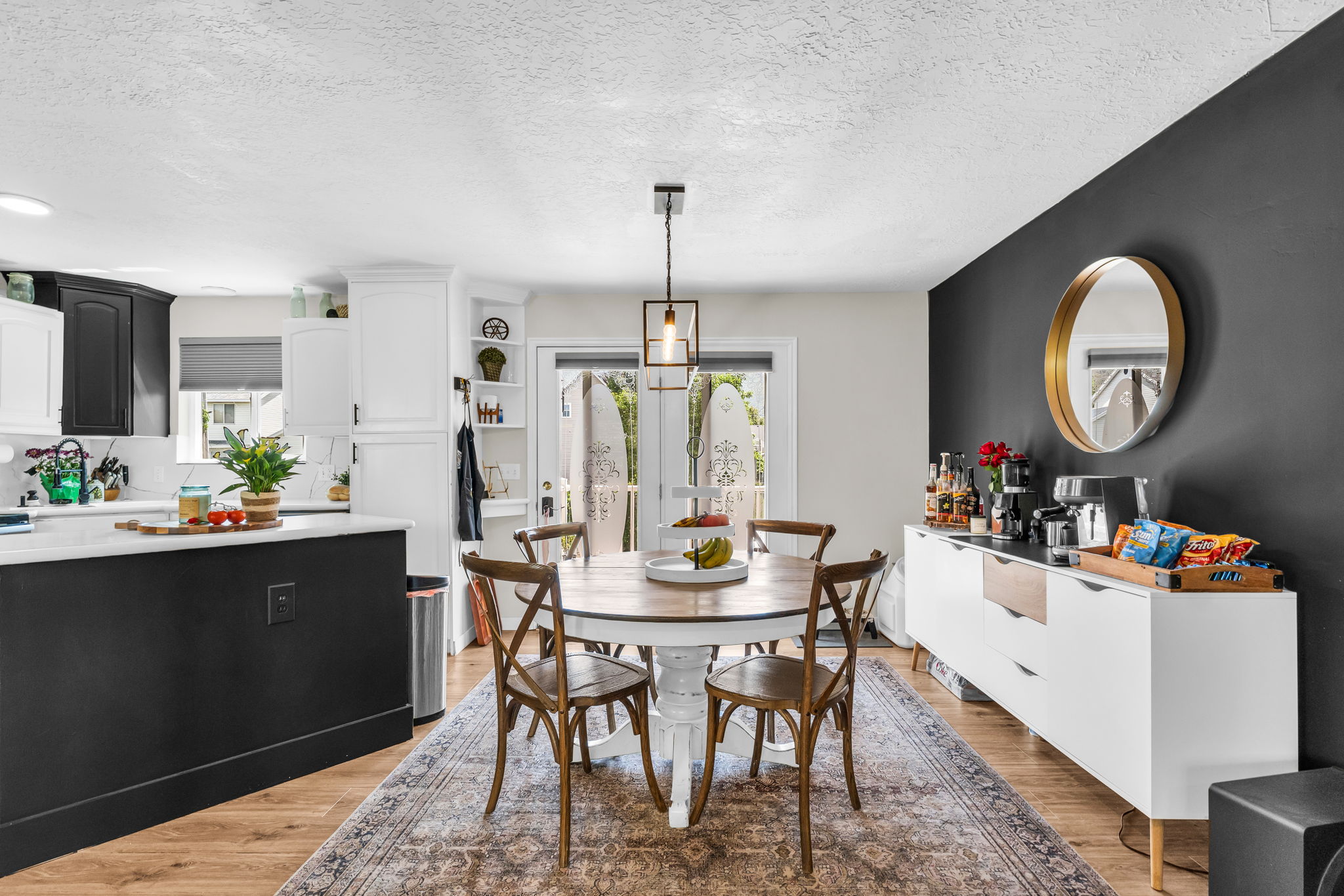 Open-concept dining area featuring wood-finish flooring, a contemporary ceiling light fixture, a dark accent wall, and French doors