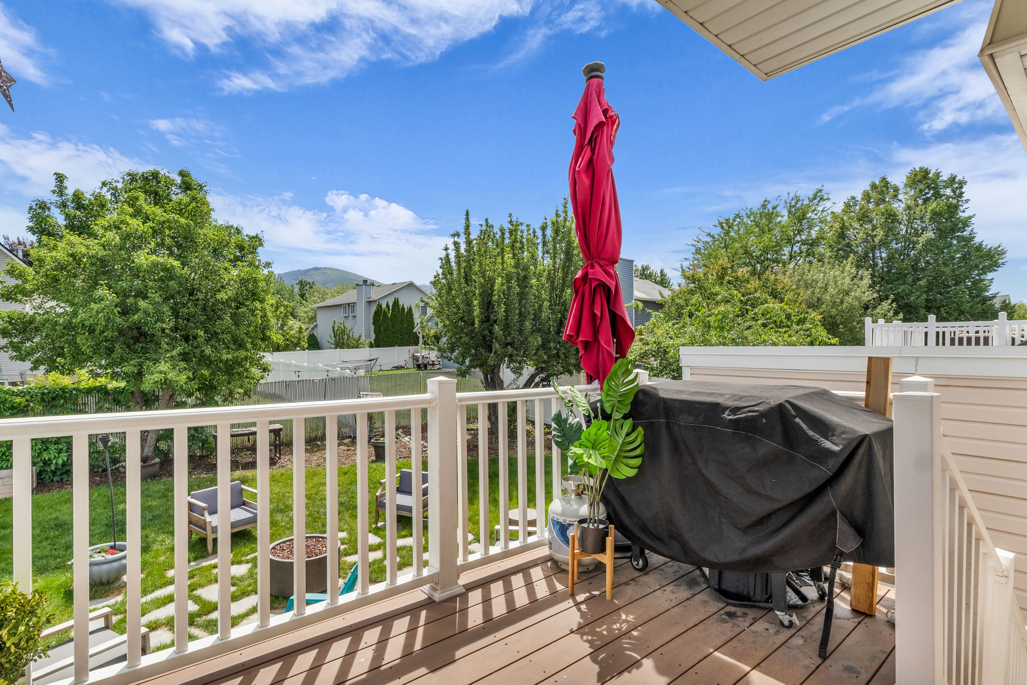 Elevated wood-finish deck with white railings overlooking a private backyard