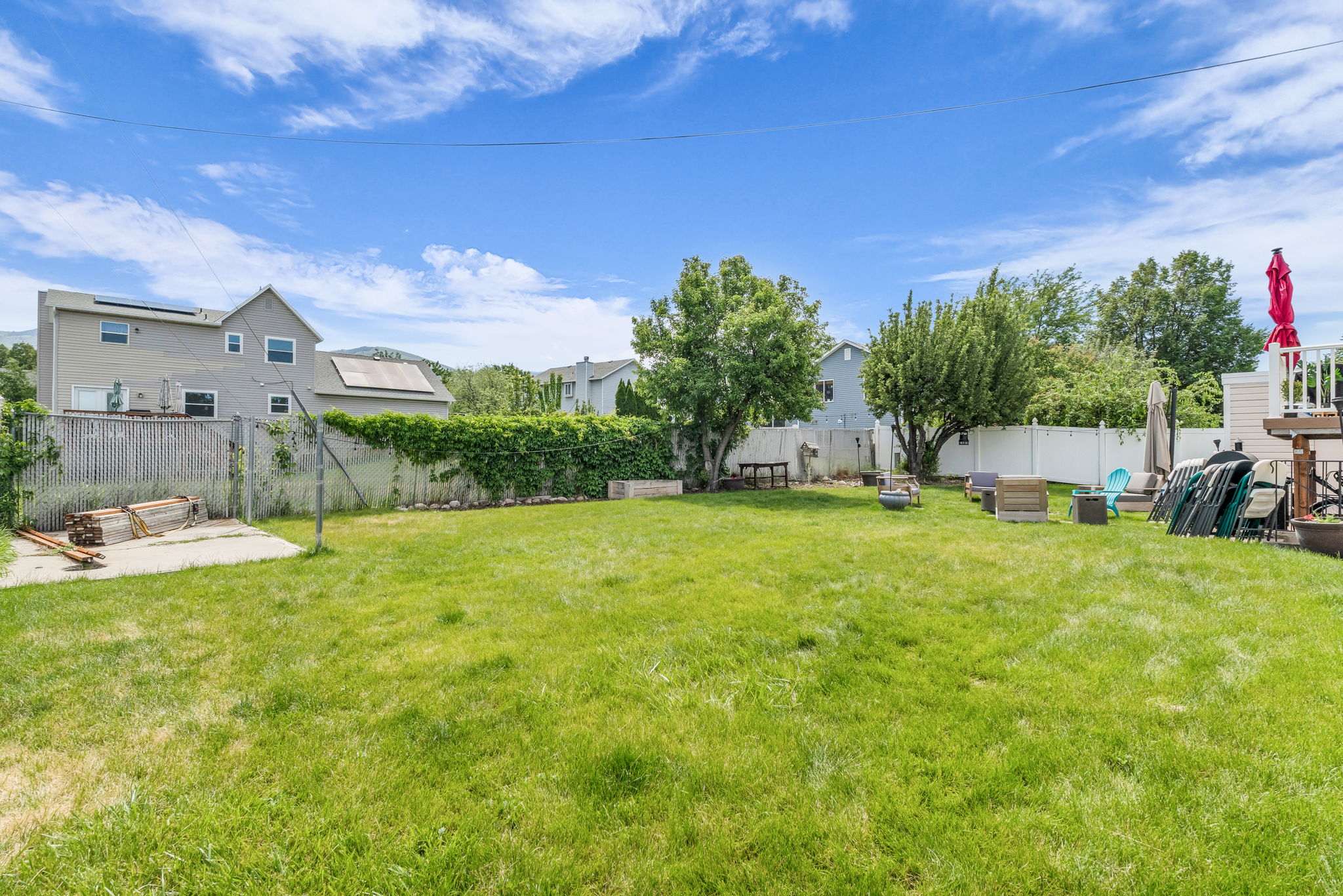 Expansive grassy yard area with mature perimeter trees and a privacy fence