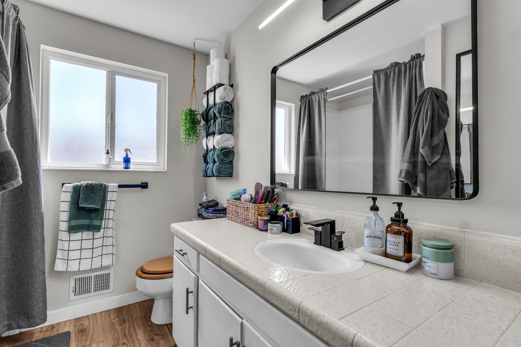 Bathroom vanity featuring a rectangular framed mirror with a black finish, a single sink, and a tile countertop