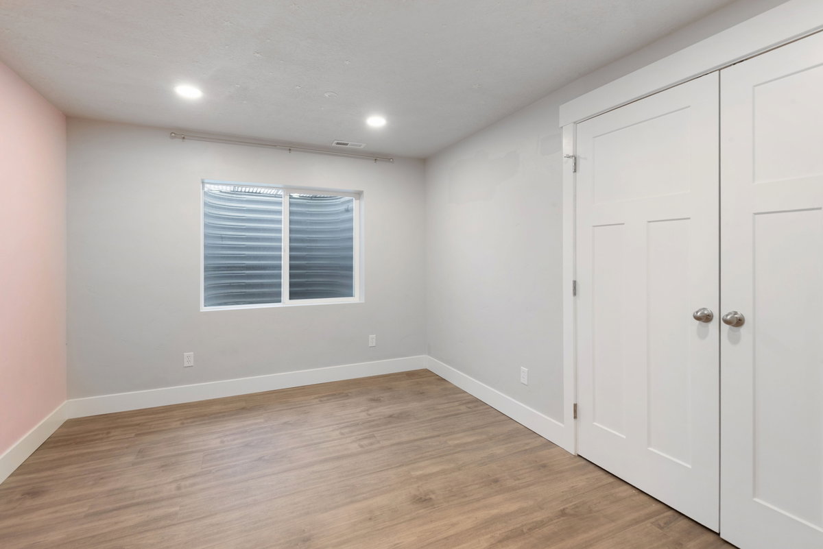 Recessed lighting illuminates this room, featuring wood-finish flooring, a window with horizontal blinds, and a two-panel closet with brushed nickel hardware