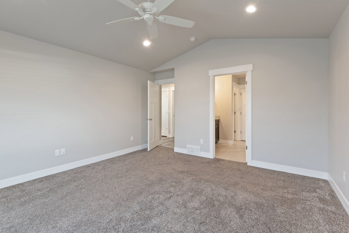 Spacious interior room featuring plush gray carpeting, white baseboards, and light gray walls