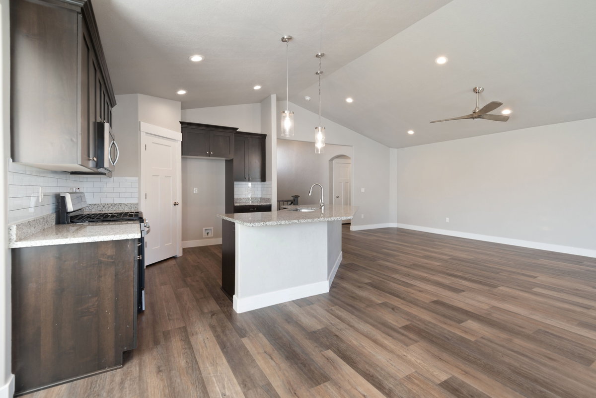 Open concept kitchen and living area featuring wood-finish flooring, vaulted ceilings, recessed lighting, and a modern ceiling fan