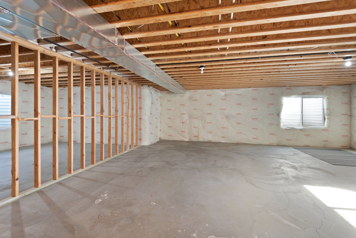 Unfinished basement featuring exposed wood joists, concrete flooring, and framed interior walls