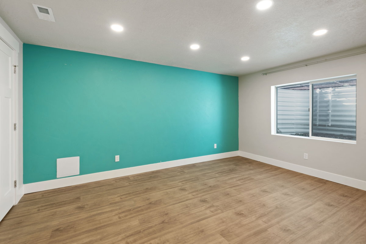 Spacious room with wood-finish flooring, recessed lighting, and a vibrant accent wall