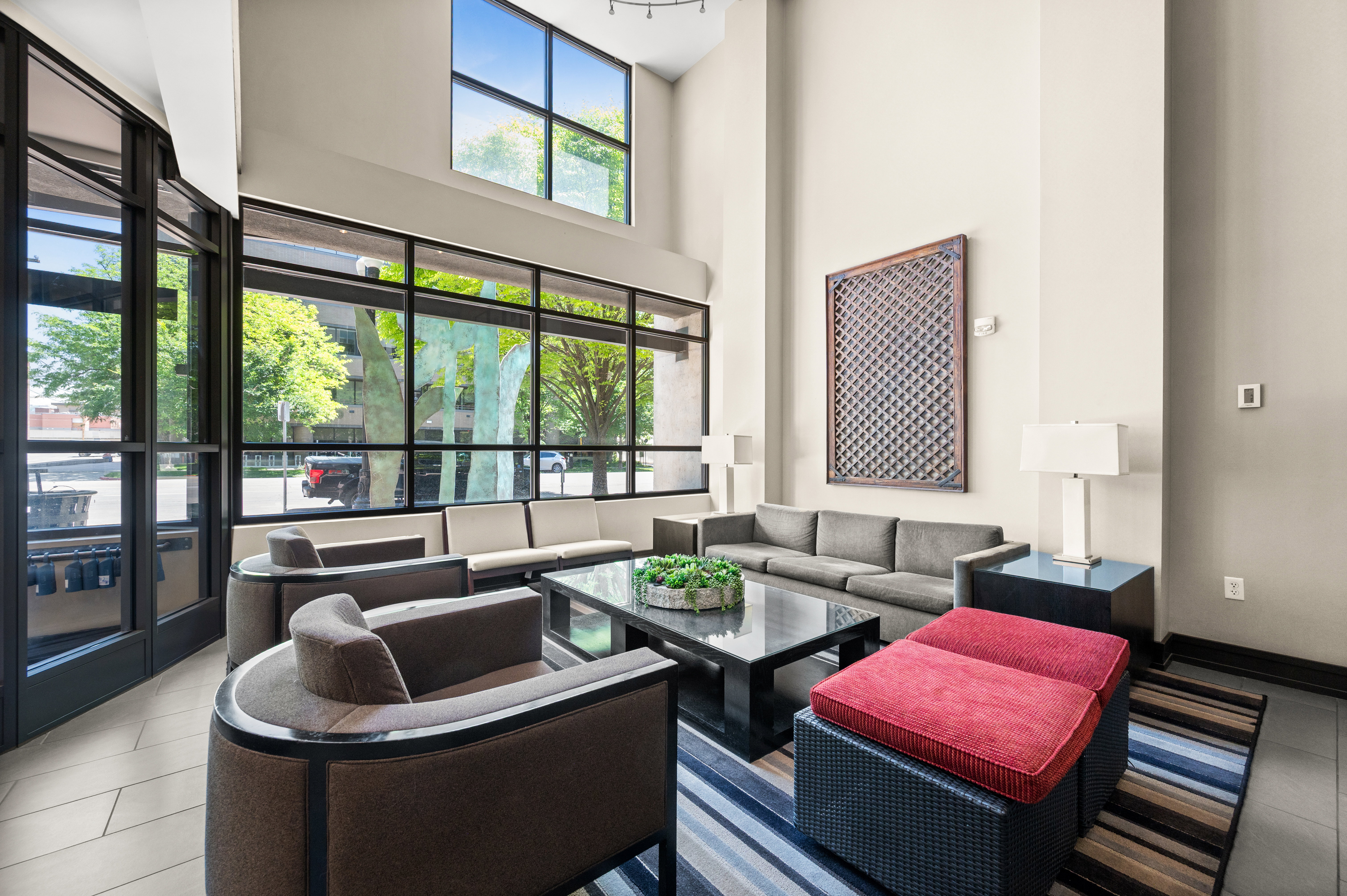 Lobby area featuring expansive floor-to-ceiling windows, high ceilings, tile flooring, and multiple seating arrangements