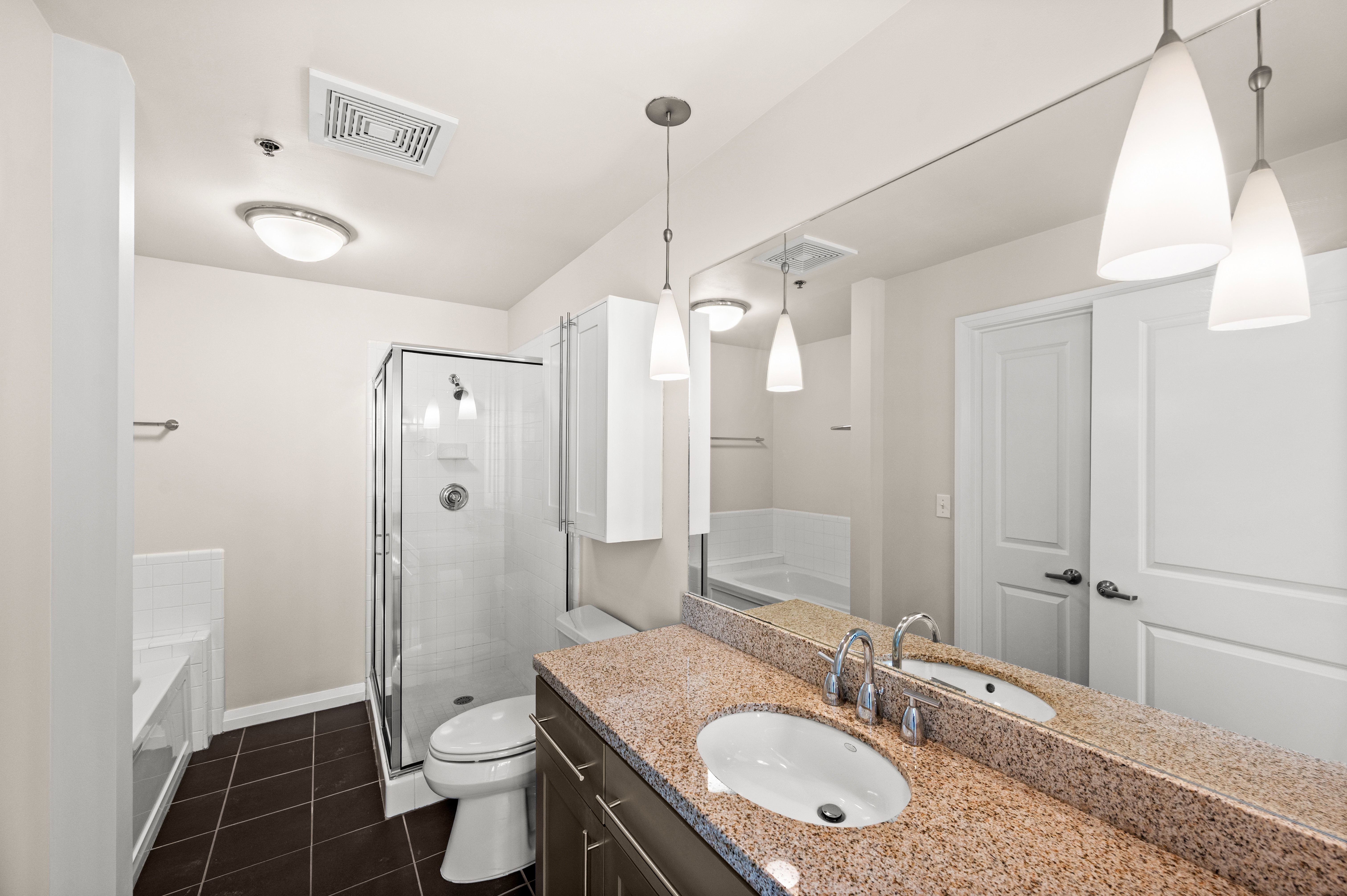 Bathroom featuring a dual-sink vanity with a granite countertop and chrome fixtures