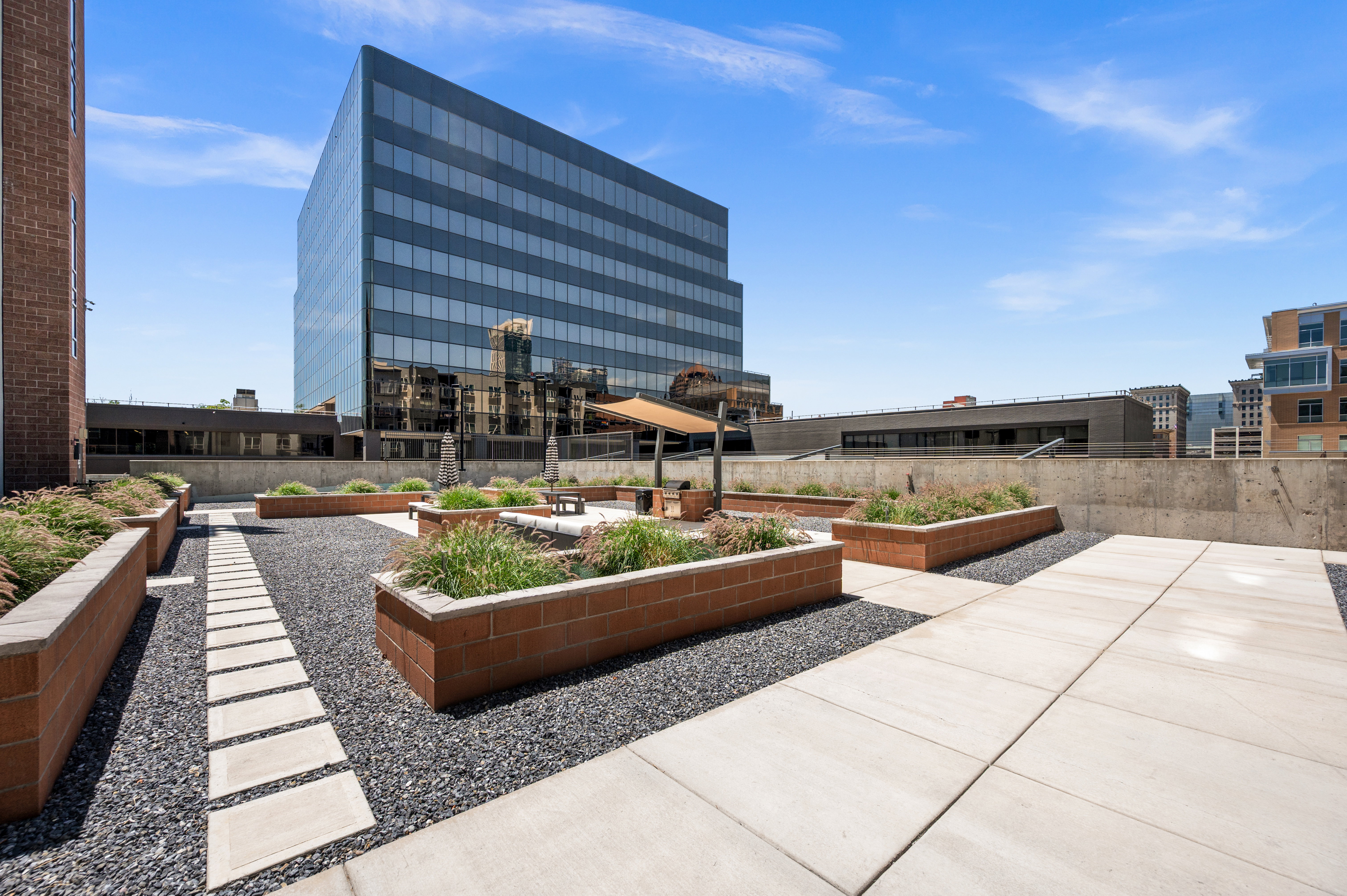 Rooftop patio featuring expansive hardscaping with integrated planters, concrete paver pathways, and a gravel ground cover