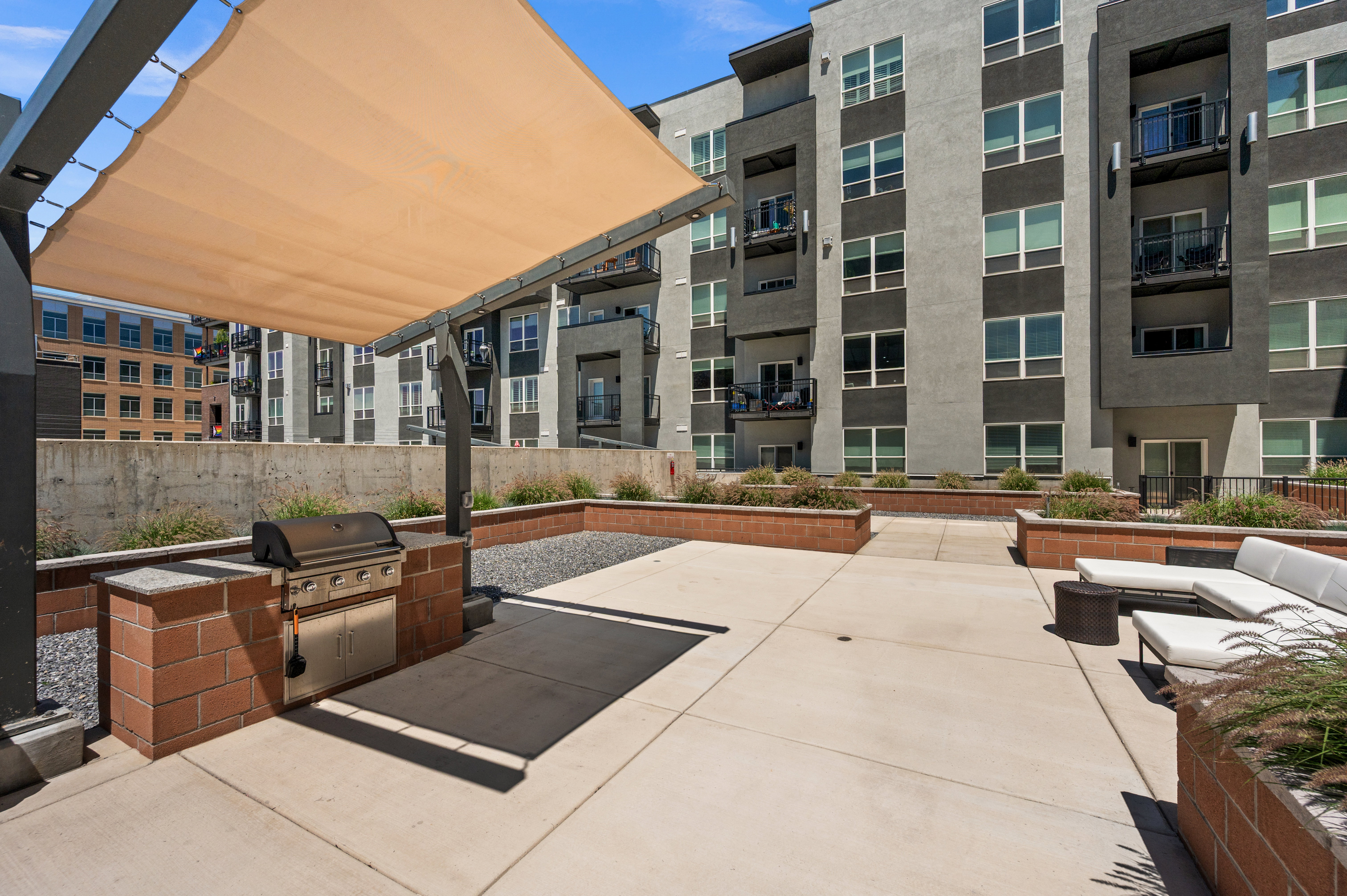 Spacious outdoor patio featuring a built-in grill station with brick accents and a sun shade structure