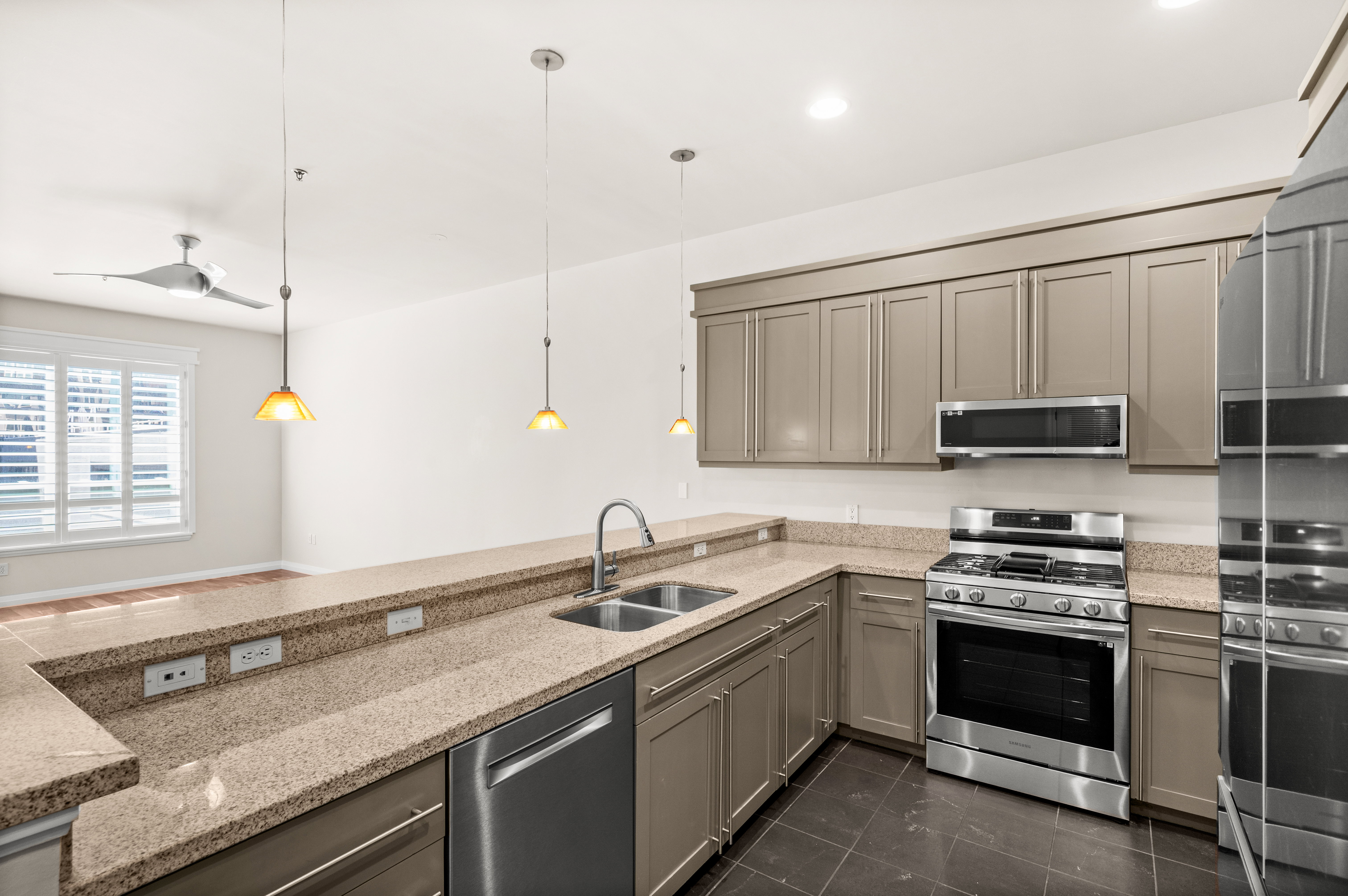 Kitchen featuring granite countertops, stainless steel appliances including a gas range and microwave, dual basin sink with a high-arc faucet, and pendant lighting