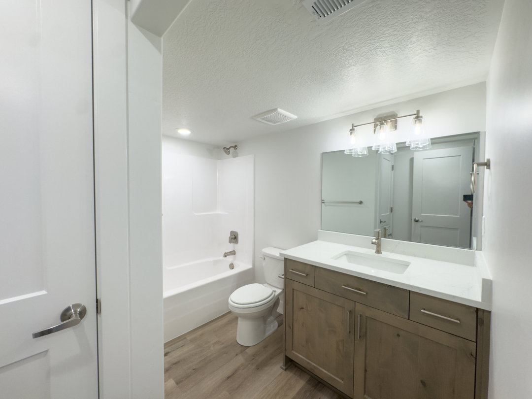 Bathroom featuring a wood-finish vanity with a light countertop, integrated sink, and brushed nickel fixtures