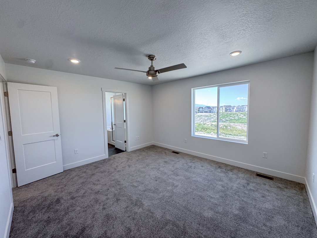 Spacious room featuring gray carpet flooring, white walls, and a large window
