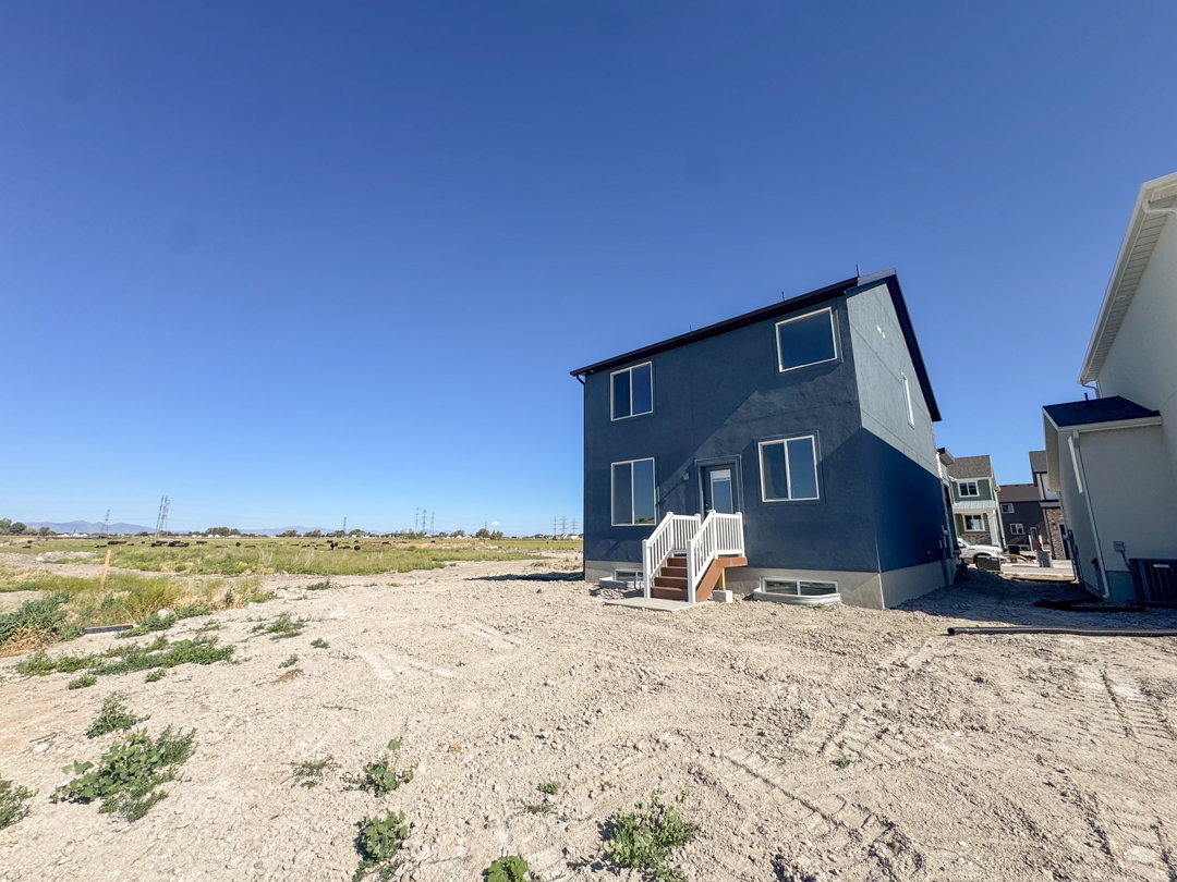 Rear exterior featuring blue siding, a white-railed staircase, and multiple windows