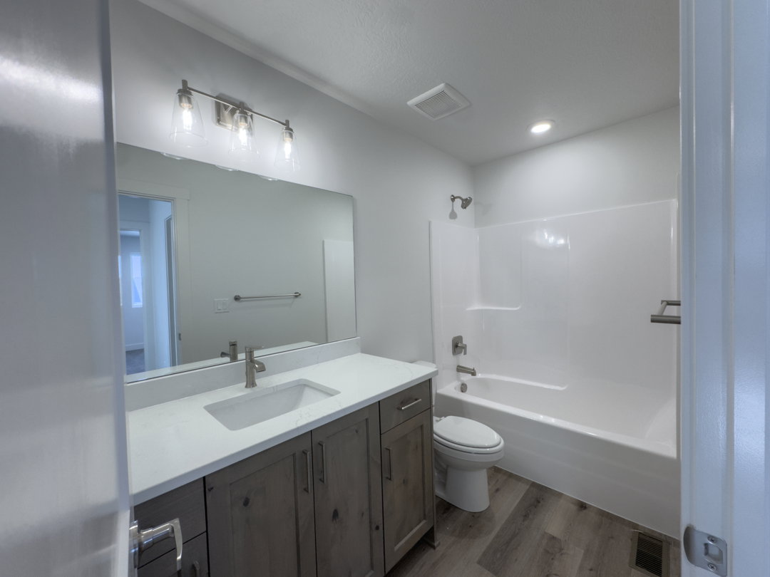 Full bathroom featuring a single vanity with wood-finish cabinetry, a white countertop, and an integrated sink