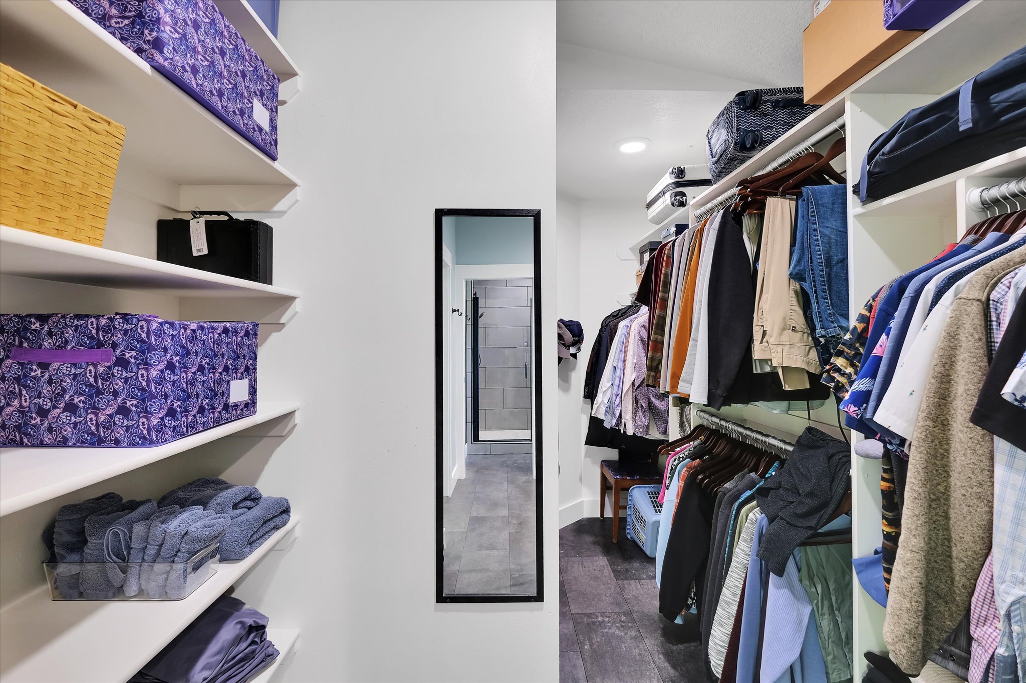 Walk-in closet featuring white built-in shelving, multiple hanging rods, recessed lighting, and dark wood-finish flooring