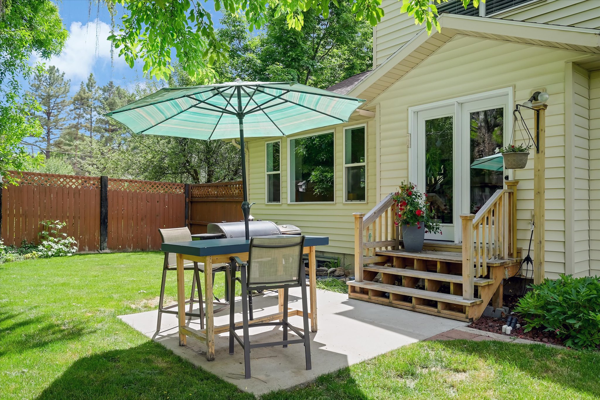 Expansive backyard featuring a manicured lawn, concrete patio, and mature perimeter fencing