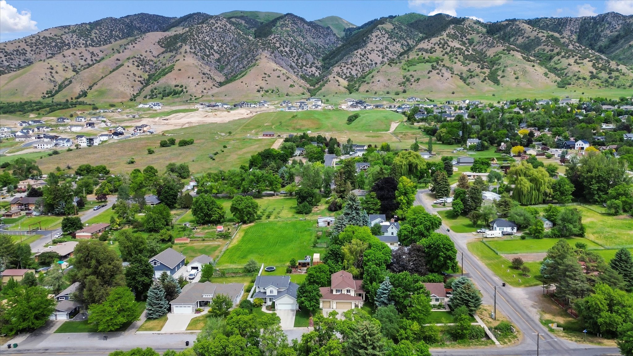 Expansive aerial landscape featuring a residential area nestled against a prominent mountain range