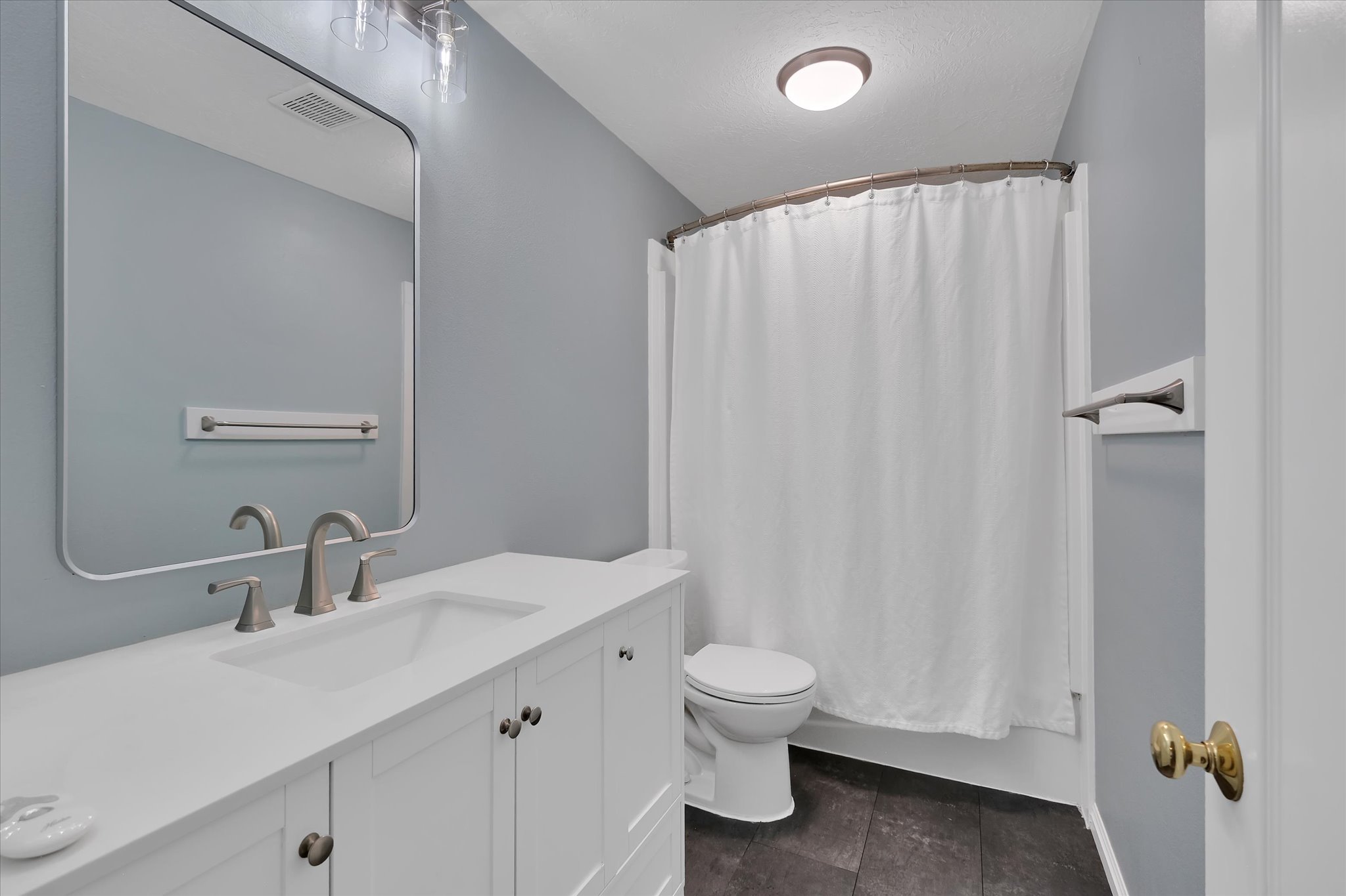 Bathroom featuring a white vanity with brushed nickel hardware, an undermount sink, and a rectangular mirror