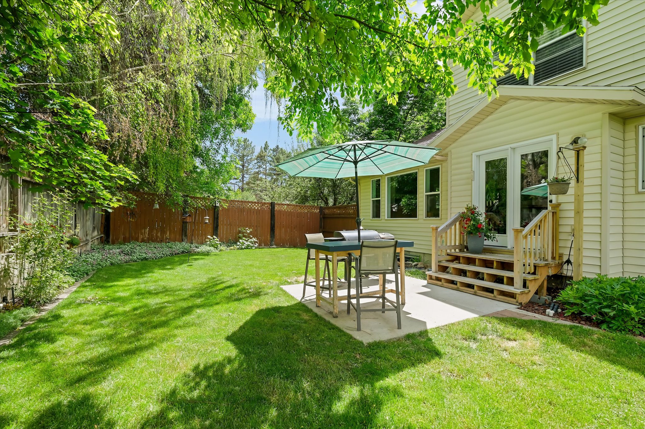 Expansive green lawn with mature trees and a privacy fence